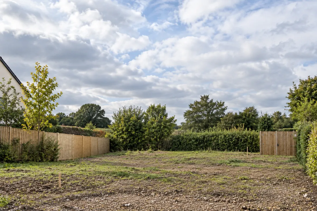 Empty, levelled building plot with fencing and trees